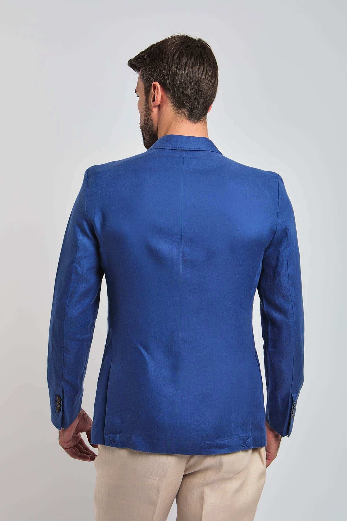 Back view of man wearing a blue tailored blazer and beige trousers