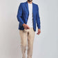 Man in a blue blazer, white t-shirt, beige pants, and white sneakers on light background
