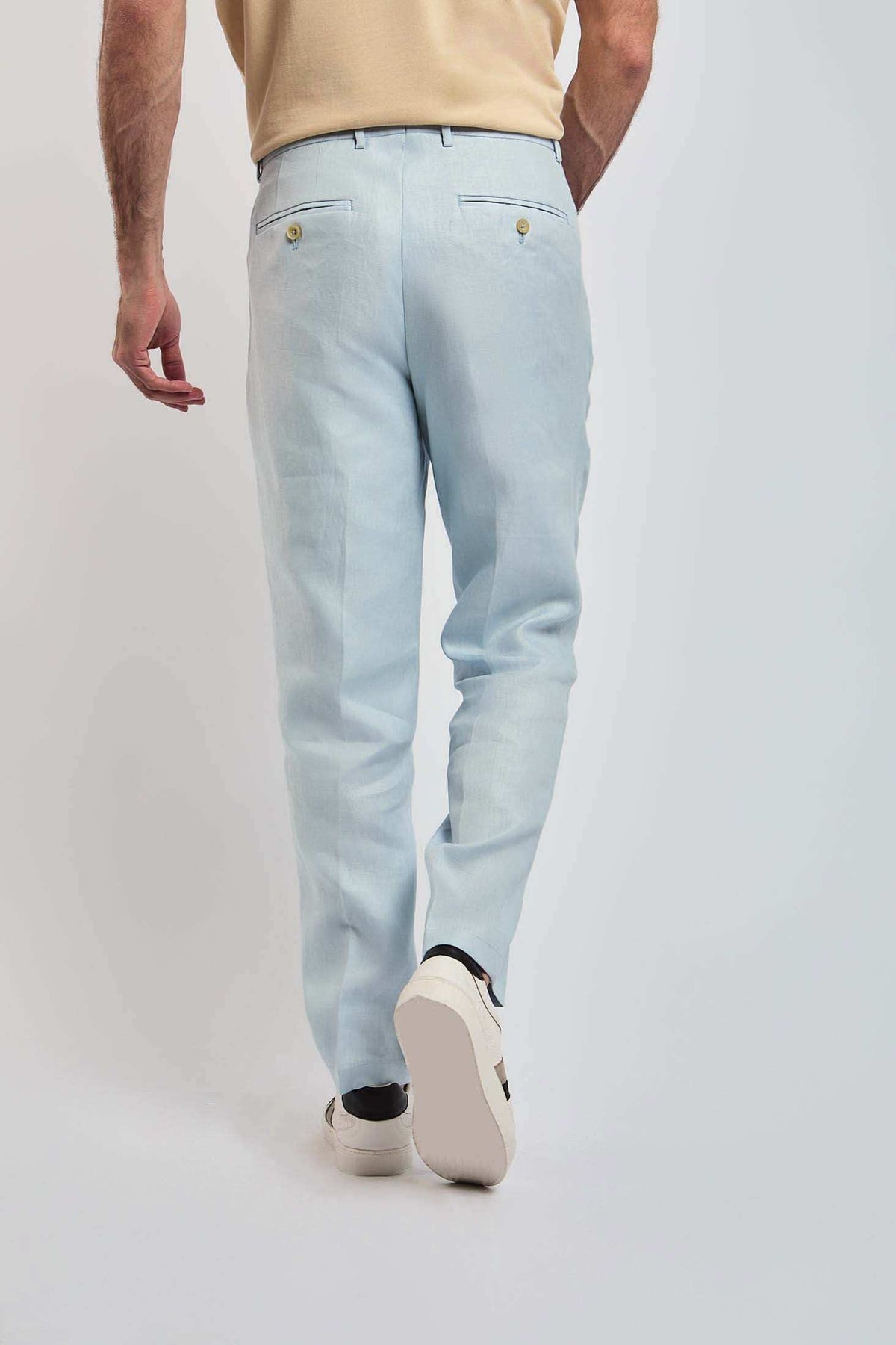 Man wearing light blue Dalydress trousers and beige shirt, rear view, casual menswear