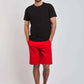 Man modeling Dalydress casual black t-shirt and red shorts with white sneakers on plain background