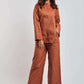 Woman wearing rust orange embroidered pantsuit with wide-leg trousers and long-sleeve top
