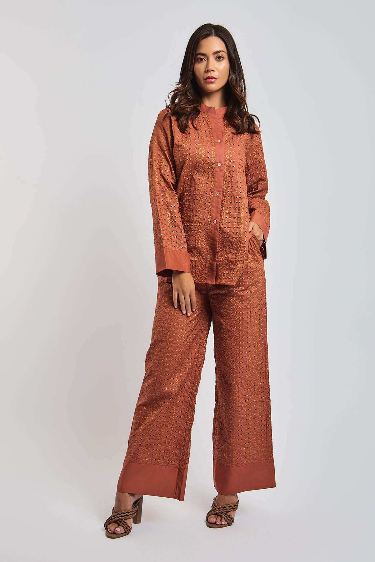 Woman wearing rust orange embroidered pantsuit with wide-leg trousers and long-sleeve top