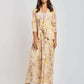 Woman wearing a long, floral yellow and pink Dalydress outfit with ruffled jacket