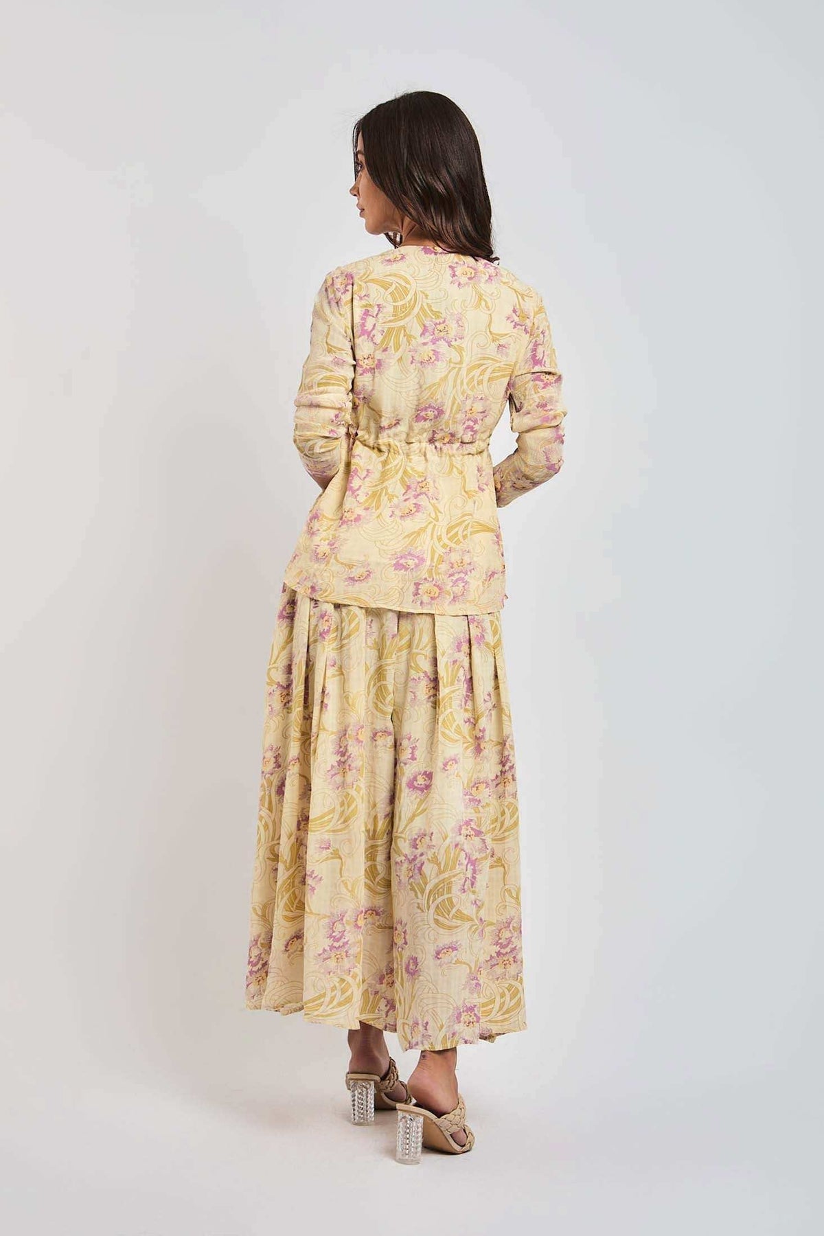 Woman wearing long-sleeve floral maxi dress in pastel yellow and pink by Dalydress
