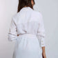 Woman modeling Dalydress white belted shirt with button cuffs and green pants, back view