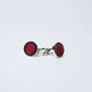 Pair of round silver cufflinks with red enamel center on a white background