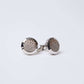 Silver round cufflinks with textured geometric pattern on white background