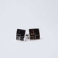Square black and silver cufflinks with geometric design on white background