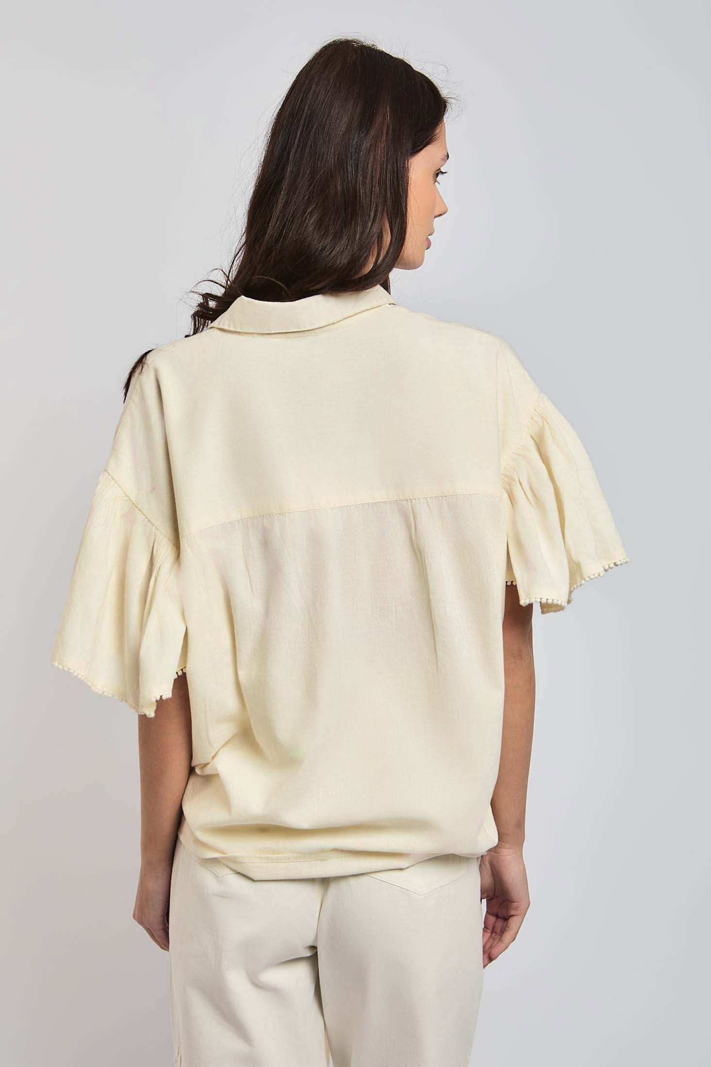 Woman wearing loose beige short sleeve blouse and matching pants, facing backwards