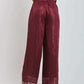 Woman wearing burgundy pleated wide-leg pants and sleeveless top, back view
