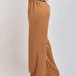 Woman wearing loose fit brown wide leg pants and white graphic t-shirt, side view
