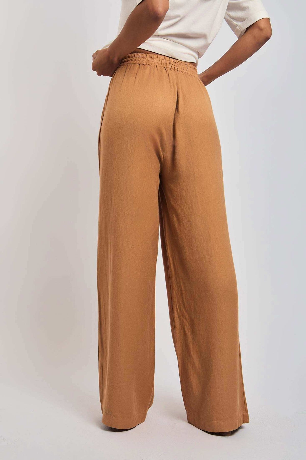 Back view of woman wearing loose-fit camel brown high-waisted wide-leg pants