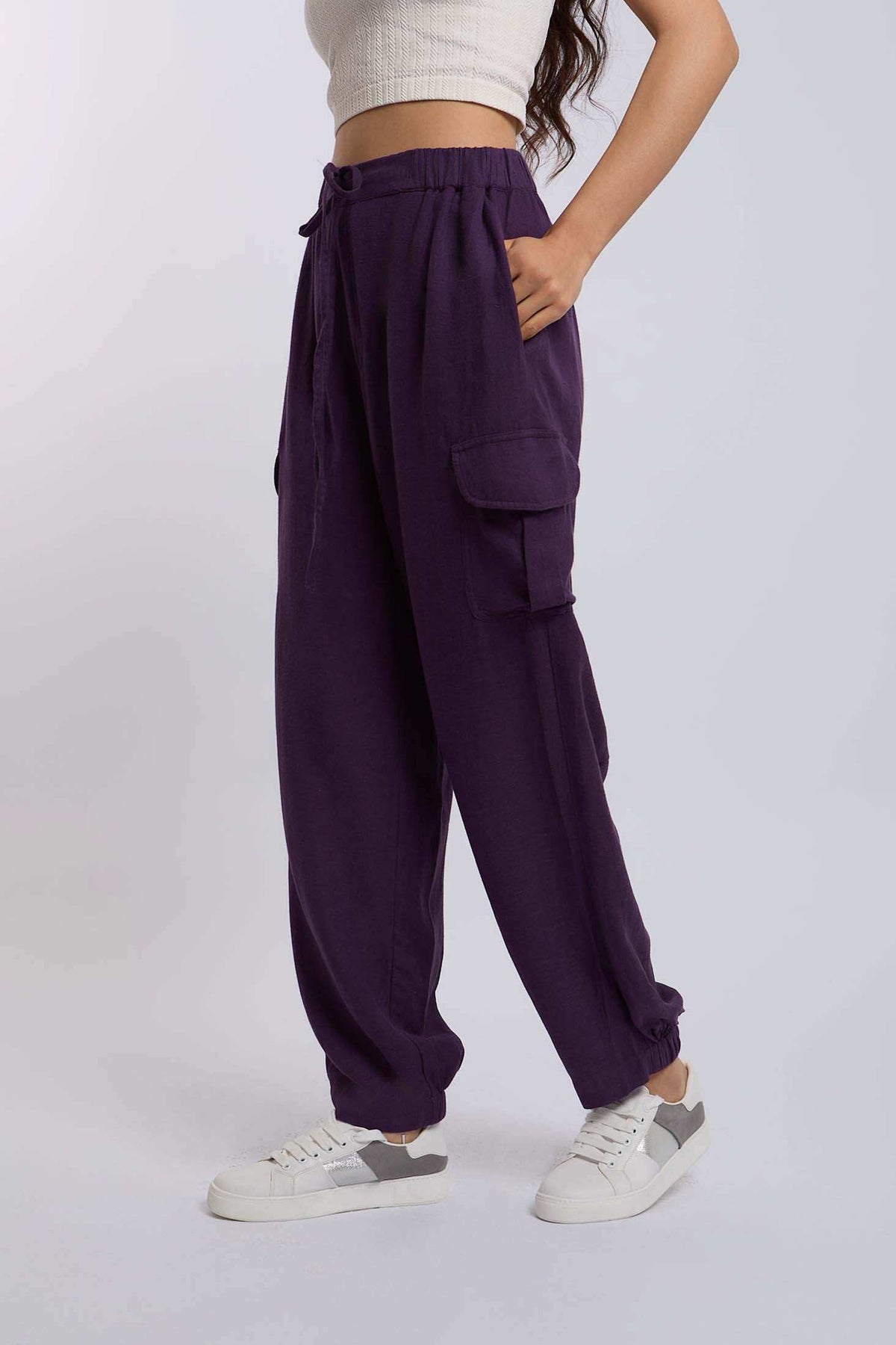 Woman wearing purple cargo pants with drawstring waist and white sneakers