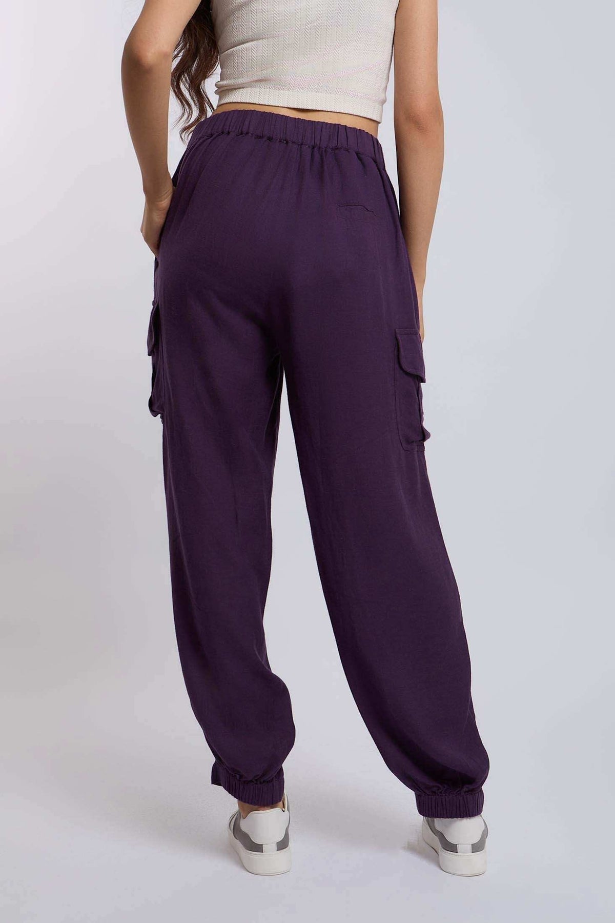 Woman wearing purple cargo jogger pants with elastic waistband and side pockets, back view