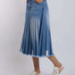 Woman wearing pleated denim midi skirt with frayed hem and casual sneakers on white background