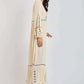 Woman in cream embroidered maxi dress with long sleeves and braided heeled sandals