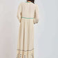 Back view of woman wearing long cream dress with embroidered hem and green accent stitching