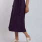 Woman wearing a purple high-waist midi skirt with tie belt and white sneakers