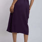 Woman wearing a high-waisted purple midi skirt with white sneakers, back view
