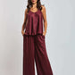 Woman wearing a burgundy wide-leg pants and sleeveless top set, standing against a plain background