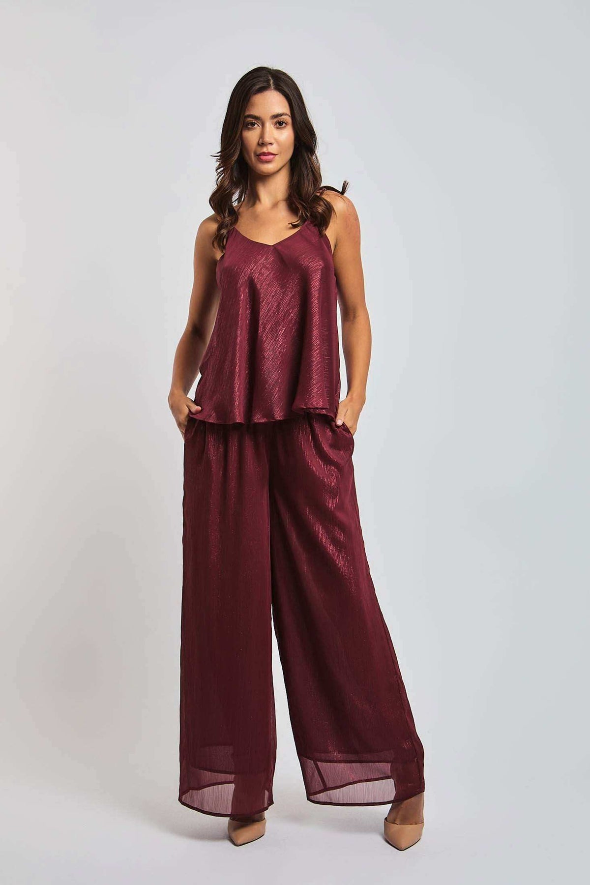 Woman wearing a burgundy wide-leg pants and sleeveless top set, standing against a plain background
