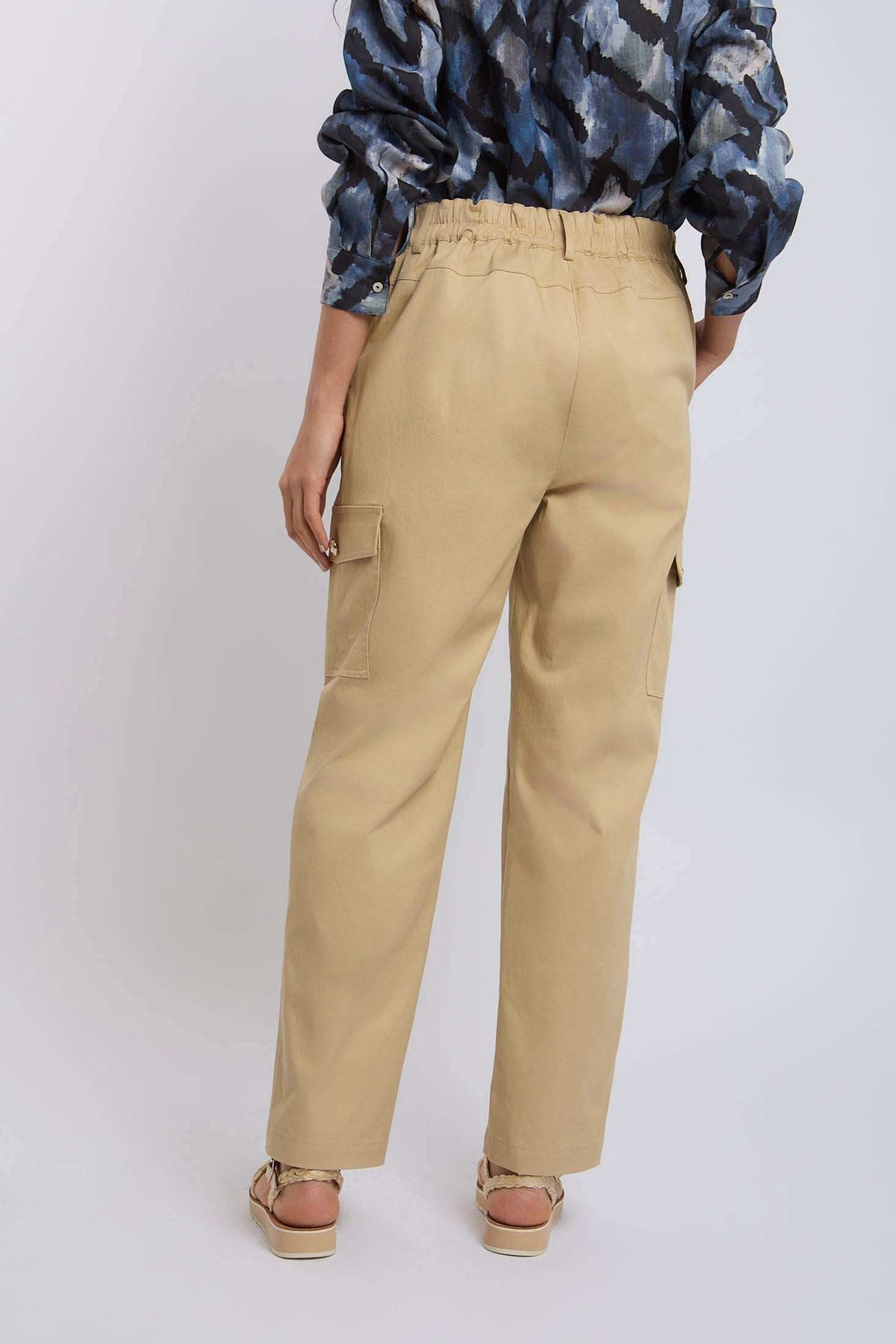 Woman wearing beige cargo pants with side pockets, back view, casual fashion style