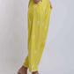 Woman wearing yellow embroidered loose pants with pockets and heeled braided sandals