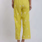 Back view of woman wearing yellow embroidered straight-leg pants, clear block heels
