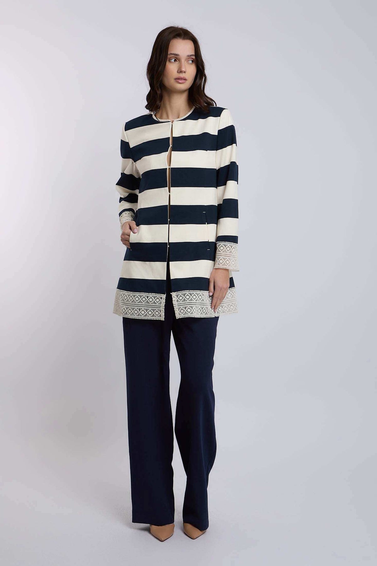 Woman wearing Dalydress navy and cream striped jacket with embroidered trim and navy pants.
