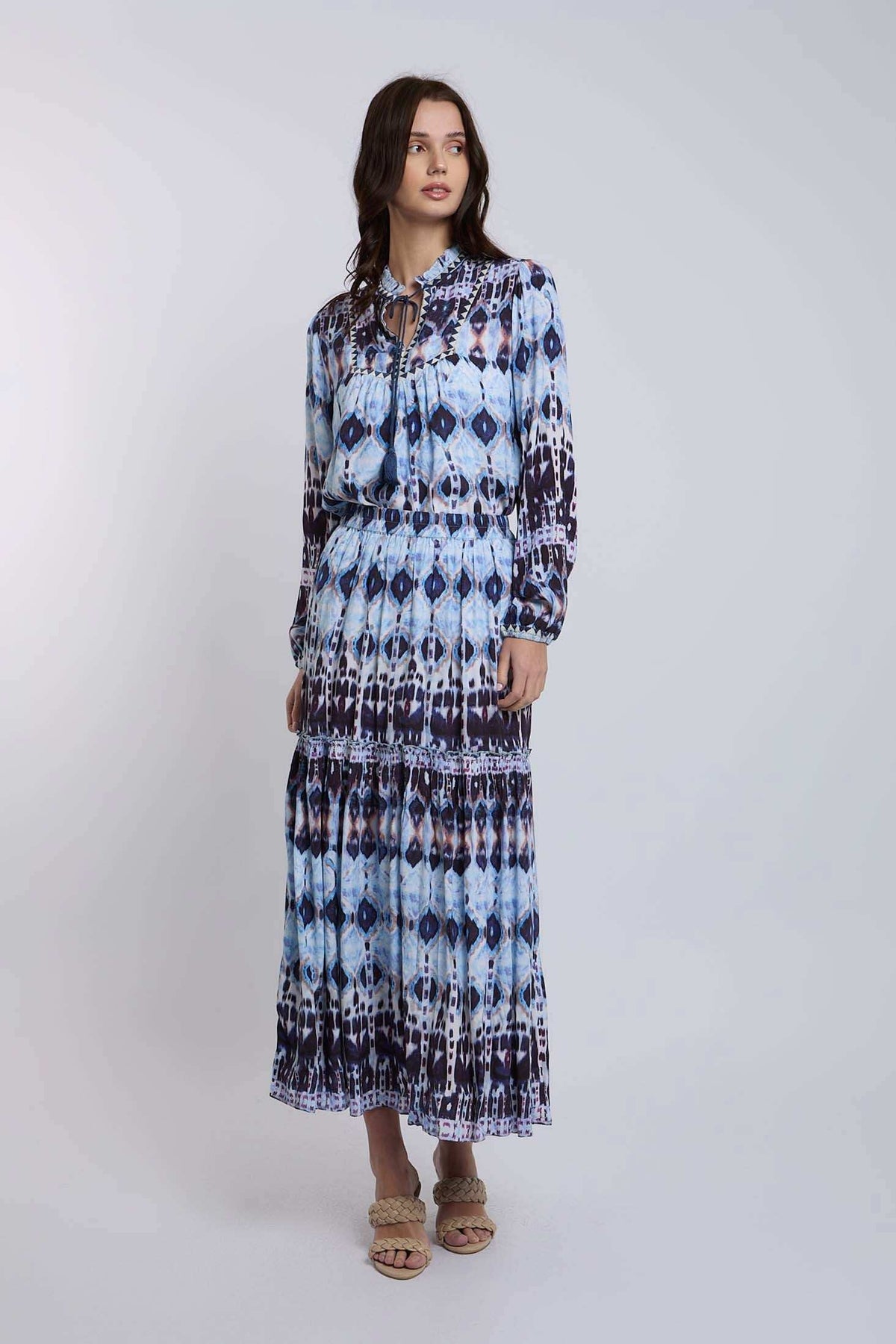 Woman wearing a long sleeve blue and white patterned maxi dress with braided sandals