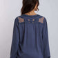 Woman wearing a long sleeve blue blouse with lace and sheer panel details on the back