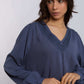 Woman wearing a blue long sleeve blouse with V-neck and textured trim detail