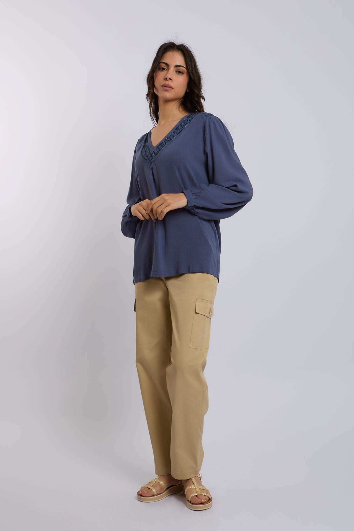 Woman wearing a blue long-sleeve blouse with v-neck and beige cargo pants