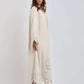 Woman in cream long dress with laser-cut floral hem and sleeves, block heel sandals