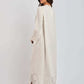 Woman wearing a long cream dress with lace cutout details on sleeves and hem