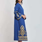 Woman wearing a blue dress with gold geometric patterns and flared sleeves, standing sideways