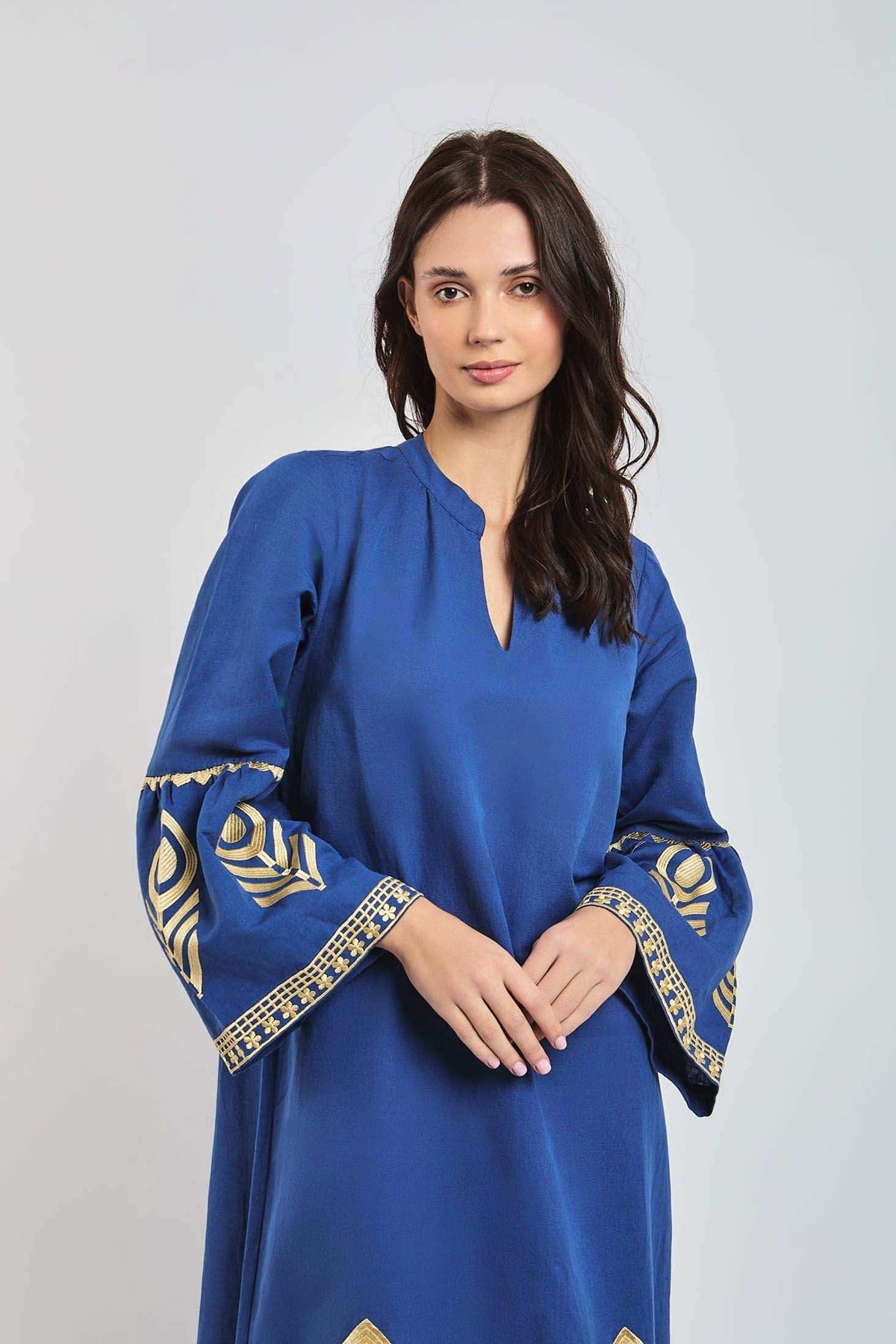 Woman wearing blue long-sleeve dress with gold embroidered patterns on the sleeves