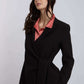 Woman wearing a black tailored blazer with tie waist over a pink collared blouse