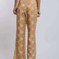 Women's patterned wide-leg pants in tan with pink and orange floral motifs, back view