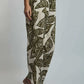 Woman wearing high-waisted beige and green leaf print pants with heeled sandals