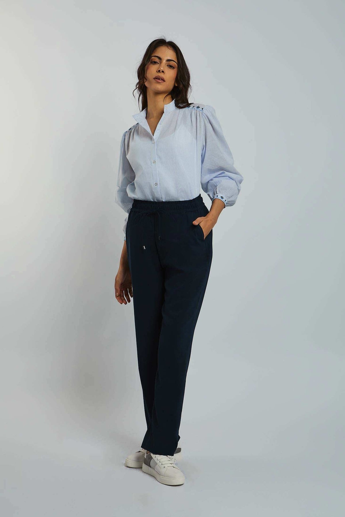 Woman wearing light blue button-up blouse with puff sleeves and navy casual pants