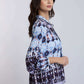 Woman wearing a blue and purple patterned blouse with long sleeves, side view