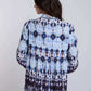 Woman in long sleeve blue and black patterned blouse and skirt, back view, casual style