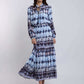 Woman wearing a long-sleeve, blue patterned maxi dress with flowy skirt