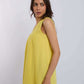 Woman wearing sleeveless yellow top and blue jeans against plain background
