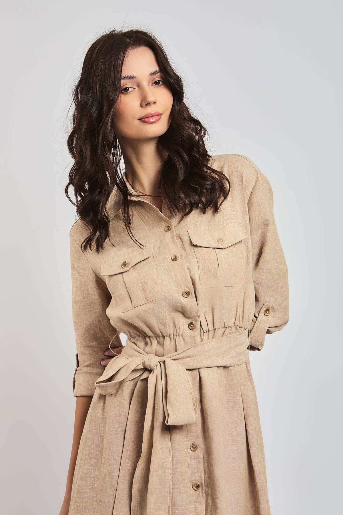 Woman wearing beige belted shirt dress with long sleeves and front button closure