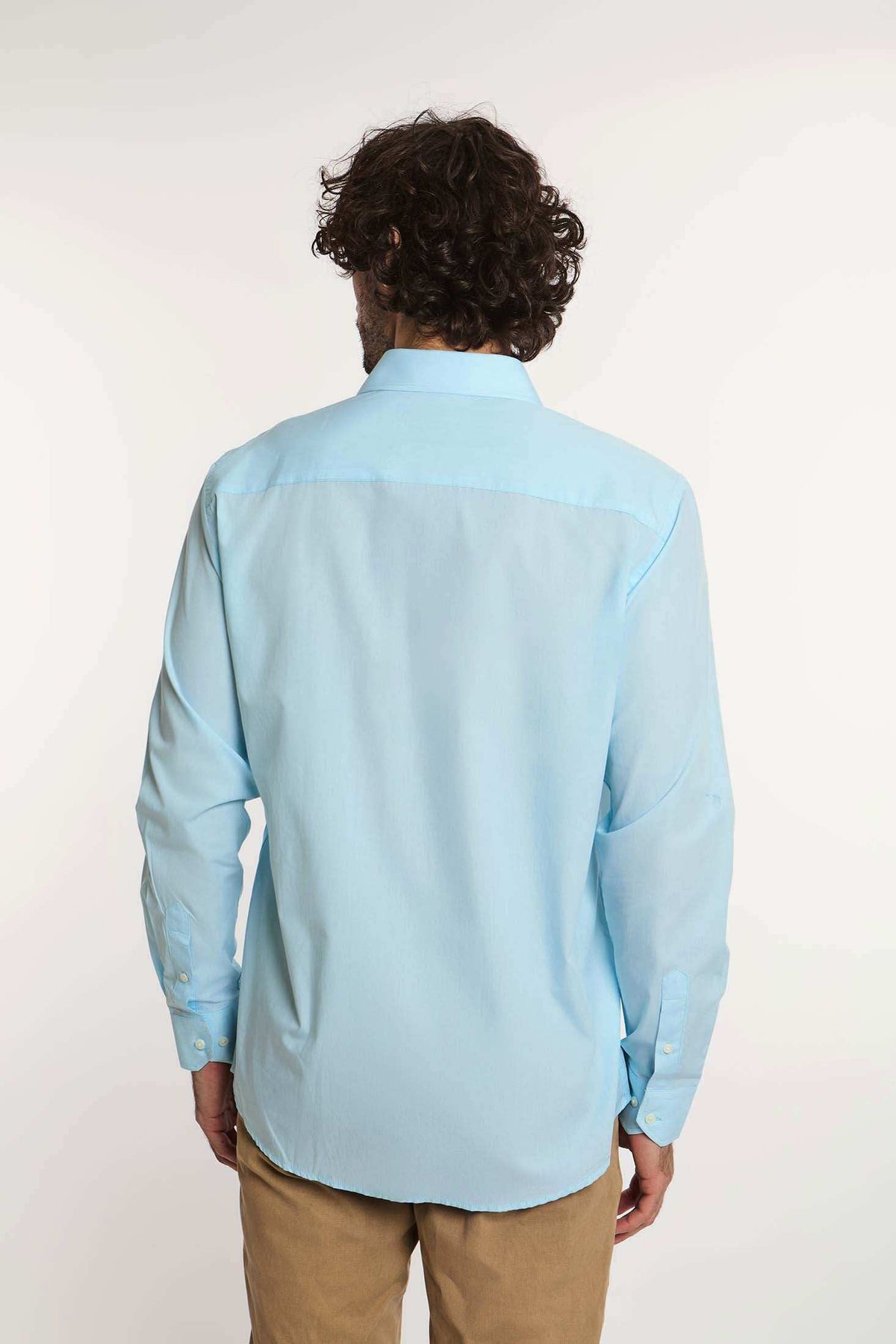Man wearing light blue long sleeve Dalydress shirt and khaki pants, shown from the back
