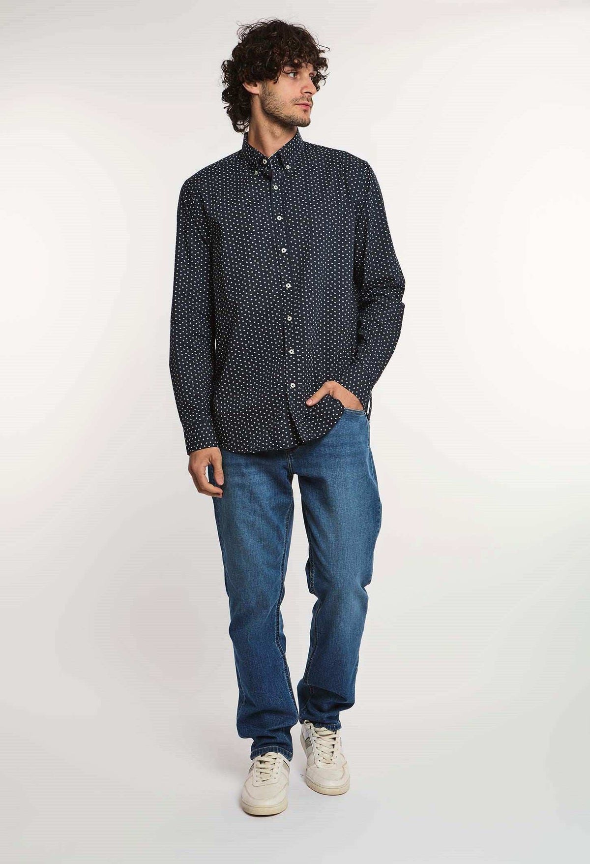 Man modeling Dalydress men's navy polka dot shirt with blue jeans and white sneakers