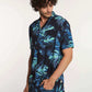 Man wearing short-sleeve navy tropical leaf print shirt and blue jeans
