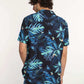 Man wearing blue tropical leaf print short sleeve shirt and denim jeans, back view